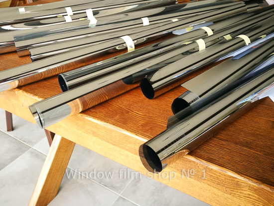Rolls of window film of different types stacked on a wooden trestle